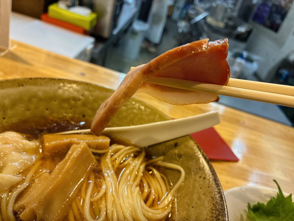 上の写真と同じチャーシュー1枚を横から撮影。薄さがよく分かります。