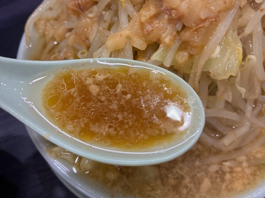 レンゲですくったスープ。表面には油が浮かびます。